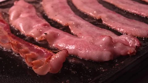Sizzling delicious bacon being flipped on hot greasy frying pan. 스톡 동영상 334642248