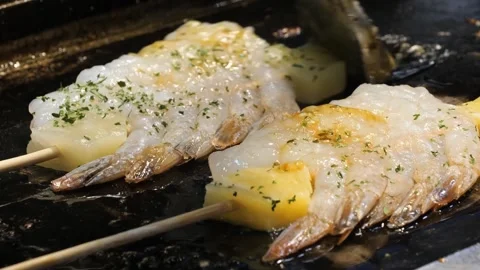 Sizzling Fresh Shrimp and Pineapple Skewers Grilling on a Hot Plate with Herbs Stock Footage 337440829