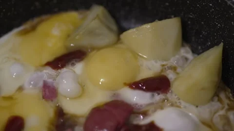 Sizzling fried eggs and sausage slices browning in a pan Stock Footage 333651489