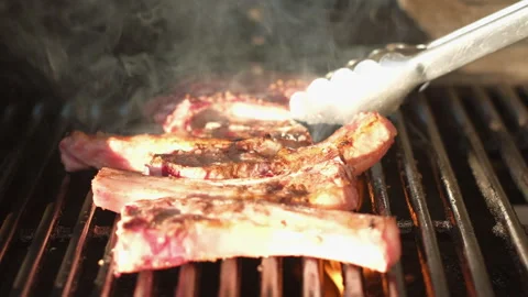 Sizzling lamb chops turned with tongs on hot barbecue and then seasoned Stock-Footage 331987605