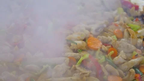 Sizzling meat with vegetables stir-fried in a large panin 4k slow motion 120f Stock Footage 283250491