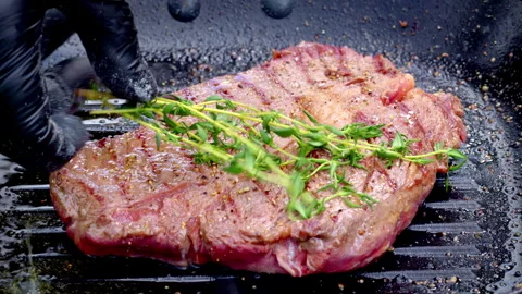 Sizzling steak with grill marks and aromatic herb toppings Stock Footage 325840025