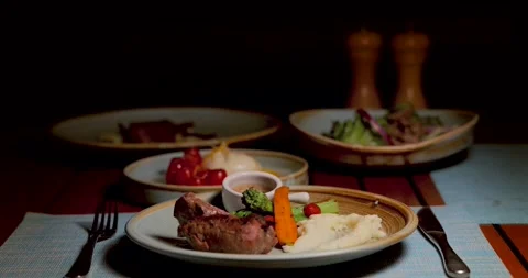 Sizzling steak with mashed potatoes, vegetables, and sauce on elegant Stock-Footage 312000447