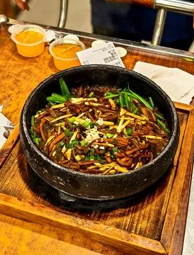 A sizzling stone pot of braised eel strips with garlic and scallions, featured a Photos