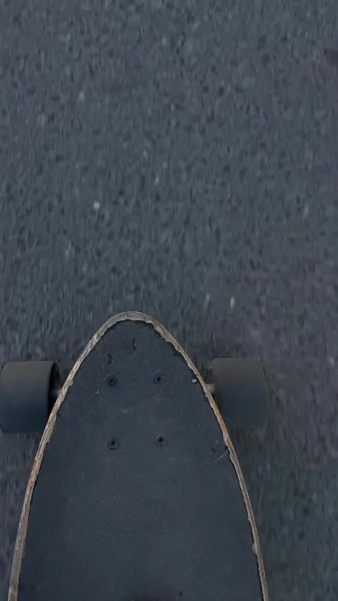Skateboard in motion on textured road surface captured from above Vidéo 336434441