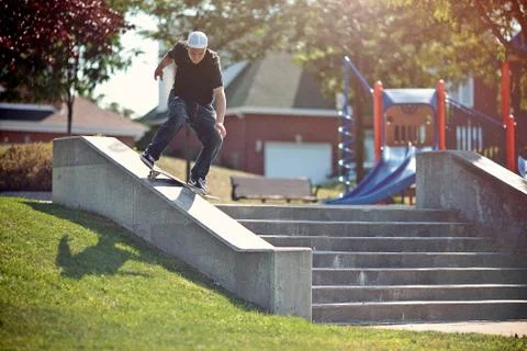 Skateboarder doing a frontside lipslide trick in a park Stock Photos