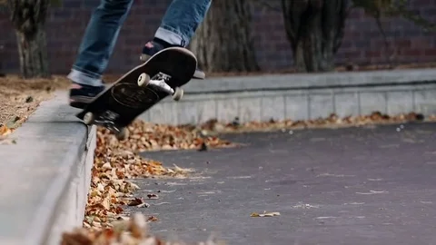 Skateboarder performs trick with fall leaves Stock Footage 76593313