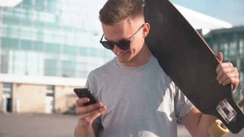 Skateboarder Texts Message on Smartphone 動画素材 91802453
