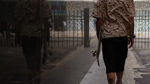 Skateboarder walking on the footpath Stock Footage 61273279