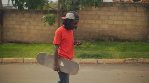  skateboarder walking in the street using cell phone slow motion shot Stock Footage 112990591