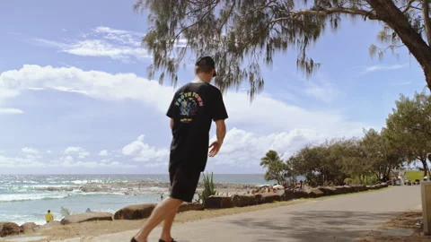 Skater at the beach with ocean in the background skating by camera. Wide shot on Stock Footage 199457088