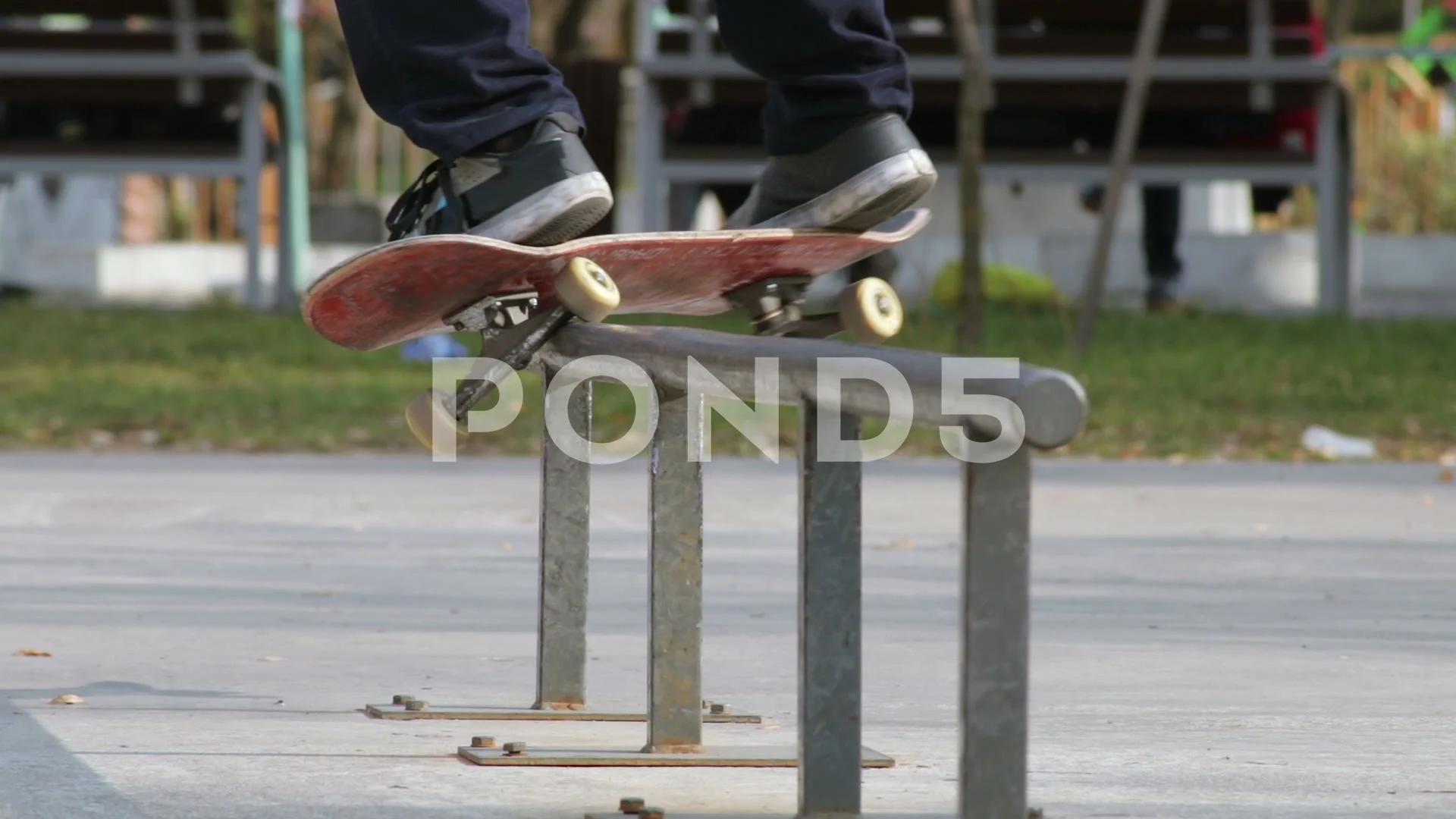 Rollerblader grinding on rail in skate park outdoors. Trick is