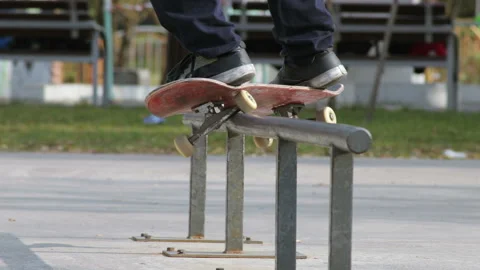Skater make grind trick feeble on rail in skatepark, close-up view in slowmotion Stock Footage 96127219
