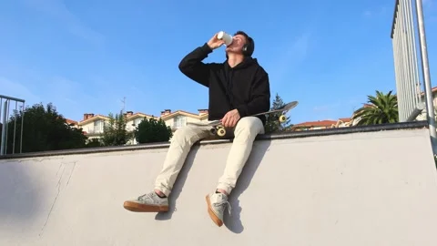 Skater Relaxing on the Half Pipe Edge, Enjoying Music and Coffee, 4k slow m.. Stock Footage 285765943