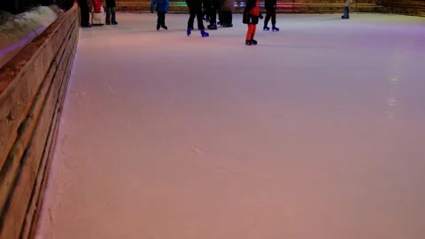 Skaters gracefully glide across a vibrant purple lit ice rink at night. 库存影片 330742940