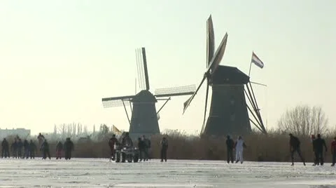 Skaters past two windmills in Kinderdijk, Holland Stock Footage 10767664