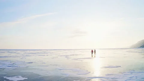 Skaters slide over smooth endless frozen lake. Natural ice rink at golden hour Stock Footage 166447669