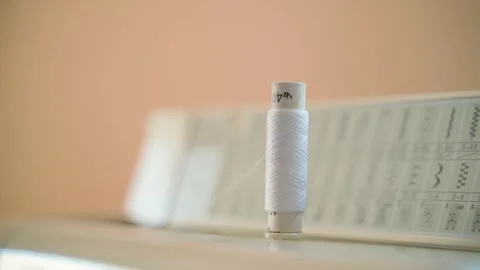 A skein of white thread rotates in a sewing machine, close-up. A spool of fine Stock Footage 261537276