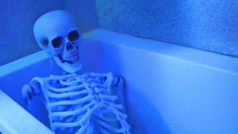 Skeleton in Bathtub with Running Shower Under Ultraviolet Light Stock Footage 276903891