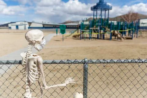 Skeleton behind fence looking at an empty closed park on a nice day Stock Photos