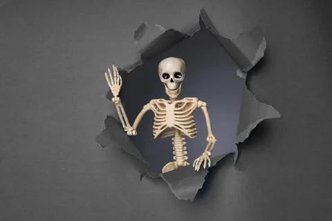 Skeleton Emerging from a Broken Wall with a Playful Gesture in a Dark Stock Photos