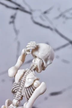Skeleton figurine touching back of head. Headache migraine, neck pain Stock Photos