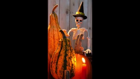 Skeleton halloween  with pumpkins and burning candle. Vertical video. Stock Footage 315780790