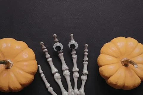 Skeleton hand between two pumpkins on dark background Stock Photos