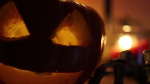 Skeleton hand crawls past glowing pumpkin as Halloween decorations come alive Stock Footage 346147357