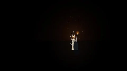 Skeleton hand moving fingers next to glowing candle flame. Stock Footage 344038476