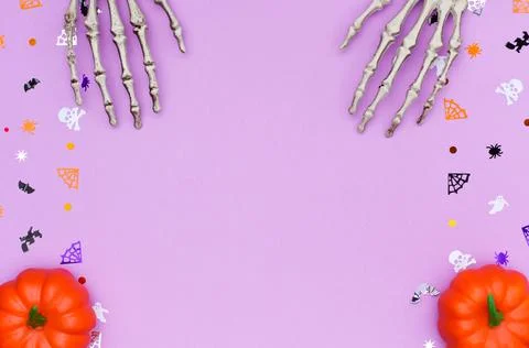 Skeleton hands and decorative pumpkins on a purple background decorated with 스톡 사진