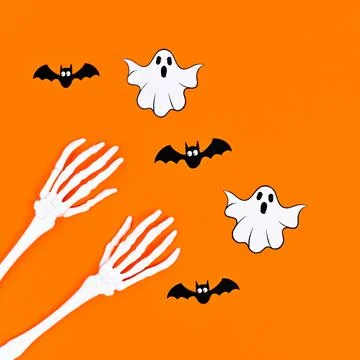 Skeleton hands with bats and ghosts on orange background. Flat lay Stock Illustration