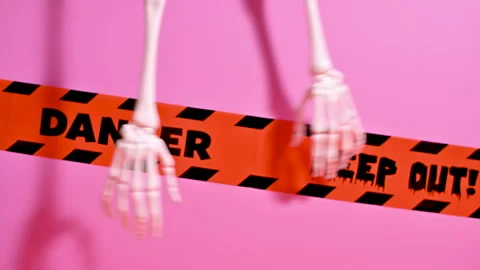 Skeleton Hands on pastel pink background with warning tapes Stock Footage 251494951