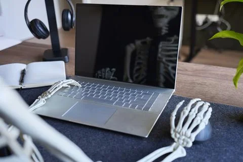 Skeleton hands using laptop and mouse at office desk with notebook and head.. Stock Photos