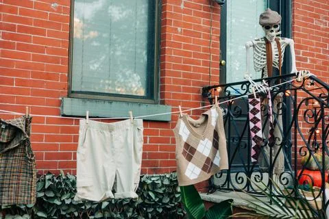 Skeleton hangs clothes on a balcony while showcasing playful Halloween 스톡 사진