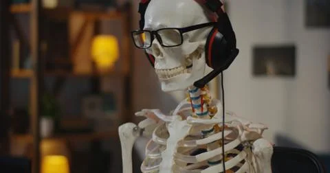 Skeleton with headphone sitting at computer Stock Photos