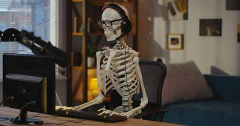 Skeleton with headphone sitting at computer Stock Photos