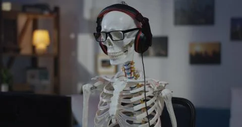 Skeleton with headphone sitting at computer Stock Photos