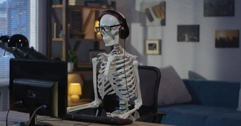 Skeleton with headphone sitting at computer Stock Photos
