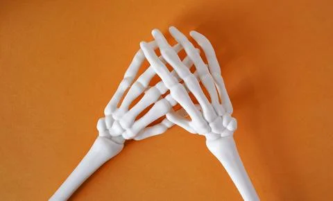 Skeleton of human hands on an orange background, top view, copy space. Halloween Foto stock