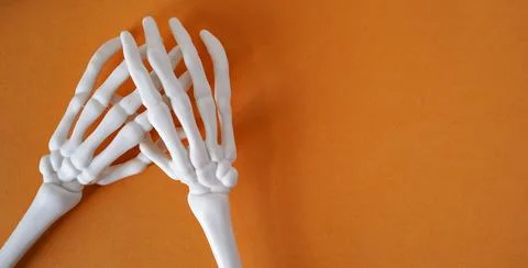 Skeleton of human hands on an orange background, top view, copy space. Halloween Stockfoto's