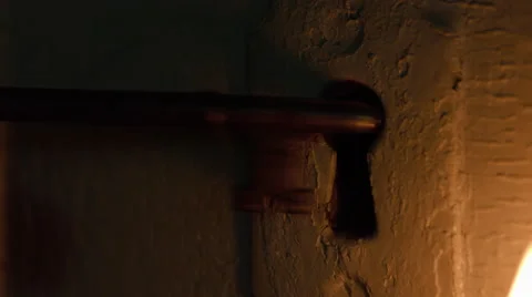 Skeleton key inserted in door by candlelight Stock Footage 63057939