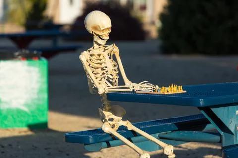 Skeleton making his move in chess Foto stock