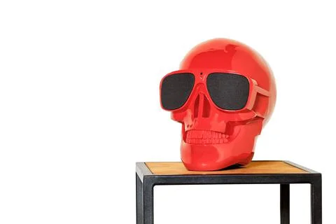 A skeleton model of a red colored human skull in black glasses stands on a me Stock Photos