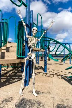 Skeleton playing on a child's monkey bars in an empty park Stock Photos