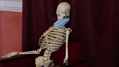 Skeleton with a protective face mask on the background of burgundy curtains. Stock Footage 134390240