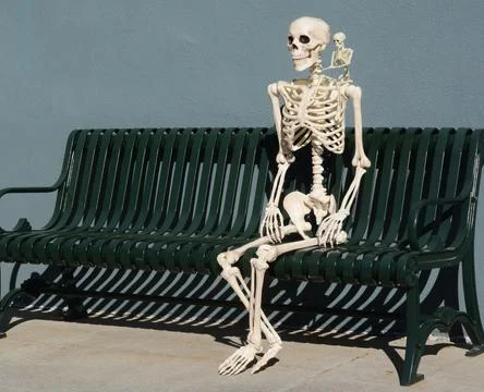 Skeleton sitting on bench with small skeleton on shoulder Stock Photos