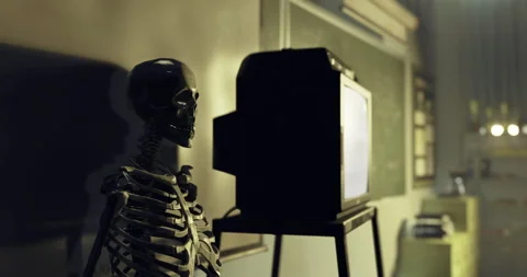 Skeleton stands next to television in an empty classroom setting Stock Footage 323937213