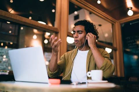 Skeptical freelancer having video chat on laptop in cafe Stock Photos