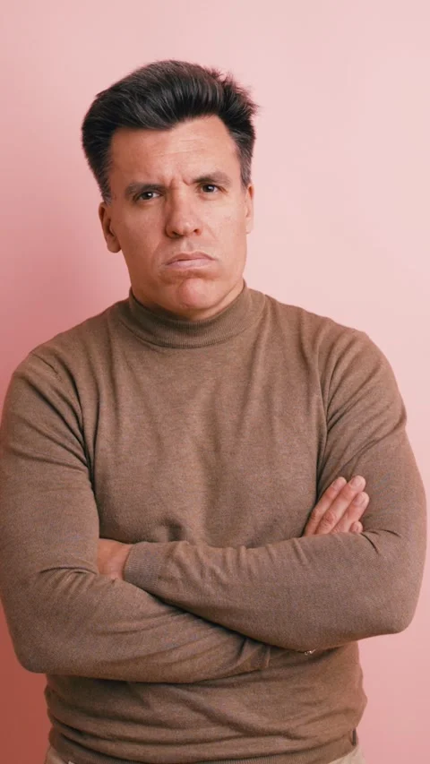 Skeptical man standing with arms crossed looking at camera. Vertical Stock Footage 341269827
